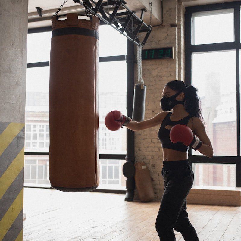 Black boxer punching heavy bag during workout in gym<br />
